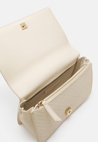 Beige Umhängetasche aus strukturiertem Material mit einem goldenen quadratischen Verschluss. Das Innenfutter verfügt über eine Reißverschlusstasche und eine glatte Innenauskleidung.