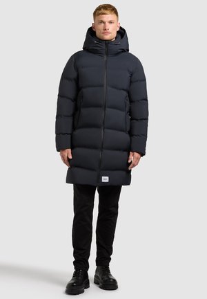 Puffer parka i mørk navy, med hætte, quiltet tekstur og lynlås i fuld længde. Inkluderer sidelommer og en logoaccent ved kanten.