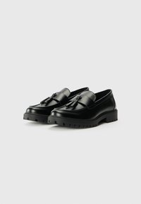 Black leather loafers with a smooth finish, featuring a decorative tassel and thick rubber soles with a textured pattern.