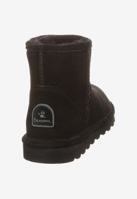 Stivale alla caviglia in suede nero con punta arrotondata e fodera morbida. Presenta una suola in gomma e il logo Bearpaw sul retro. Cuciture visibili.