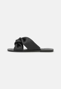 Svarta slidesandaler med en knuten remdesign, tillverkade av texturerat material. Platt sula med subtil märkning på fotbädden.