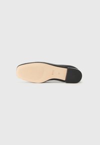 Semelle de chaussure noire avec une finition polie, présentant un gaufrage horizontal et un dessous beige clair avec du texte en relief. Design classique et épuré.