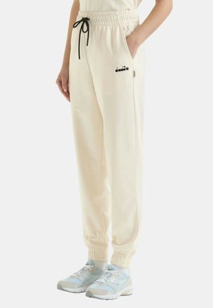 Pantaloni jogger color crema con vita elasticizzata, cordoncino regolabile, tasche laterali e logo ricamato nero sulla tasca sinistra.