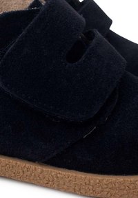 Marineblaue Textilschuhe mit einem Klettverschluss, ausgestattet mit einer strukturierten Korksohle und einem glatten Obermaterial, die ein schlichtes, funktionales Design zeigen.