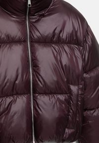 Bordeauxrote Steppjacke mit hohem Kragen, Reißverschluss und gesteppter Textur sowie einer Detailtasche vorne. Glatte, glänzende Außenseite.