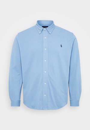 Camisa de botones de manga larga de color azul claro, hecha de algodón, con un cuello abotonado y un pequeño logotipo bordado en el pecho.