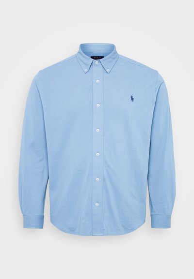 Hele helesinine puhviga nupp-särk, mis on valmistatud puuvillast, omab nuppudega krae ning rindkere piirkonnas on väike tikandiga logo.