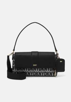 Sac à main DKNY noir et gris avec rabat en cuir texturé, logo doré, bandoulière amovible et petite pochette zippée attachée sur fond blanc.
