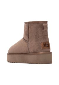 Stivali alla caviglia in suede marrone con suola piatta, punta rotonda e logo laterale. Presentano una tomaia testurizzata e una suola esterna robusta e gommata.