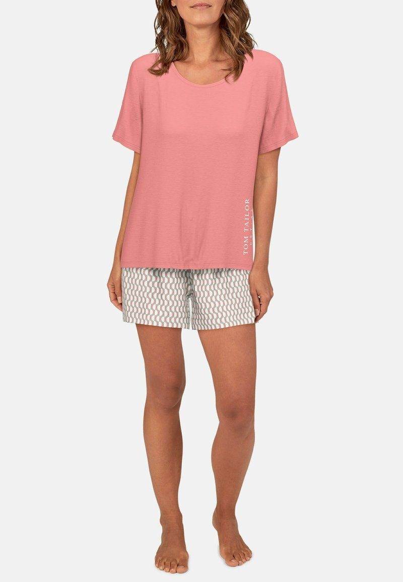 Lichtroze katoenen T-shirt met een ronde halslijn en korte mouwen, gecombineerd met gestreepde shorts met golvende patronen in gedempte kleuren.