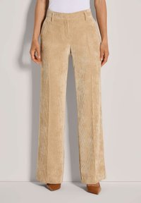 Beige corduroy wijde broek met verticale ribbels, met een platte voorkant, ceintuurlussen en een gladde textuur. Aangevuld met bruin puntige hakschoenen.
