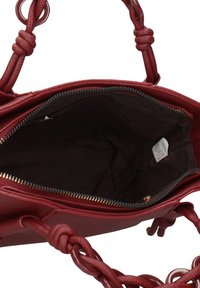 Borsa rossa in similpelle con manici intrecciati e cerniera dorata. Interno con fodera marrone e una piccola etichetta su un lato.