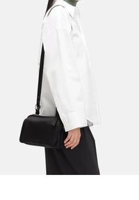 Borsa a tracolla in pelle nera con chiusura a zip, forma rettangolare, superficie liscia e tracolla regolabile. Design minimalista, senza decorazioni visibili.