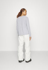 Grijze lange mouw top gecombineerd met witte broek en zwarte schoenen. De top heeft een ronde halslijn en een ontspannen pasvorm, met een gladde textuur.