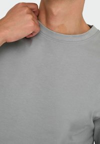 Jasnoszara bluza z okrągłym dekoltem, wykonana z miękkiej bawełny, charakteryzująca się gładką fakturą i regularnym krojem, z minimalnymi detalami przeszyć.