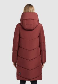Burgundy puffer coat with a chevron pattern, a large hood, and a logo patch near the hem. Made of smooth, warm material.