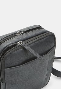 Borsa in pelle nera con finitura testurizzata, dotata di due scomparti con zip, una tasca frontale e un cinturino regolabile.