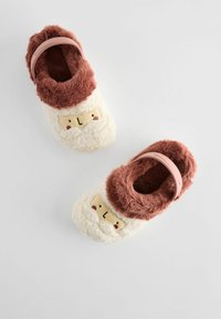 Pantofole pelose con una combinazione di colori bianco e marrone, dotate di una parte superiore in morbido pellicciotto e di una cinghia rosa. Dettagli facciali ricamati nella parte anteriore.