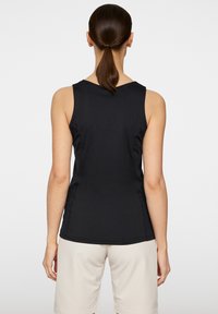 En svart ärmlös topp i mjukt tyg som har en rund halsringning och något böjd nederkant. Bakdelen är figursydd med subtila sömmar och detaljer.