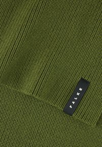 Tessuto verde a coste con una consistenza morbida, caratterizzato da strisce verticali e orizzontali a contrasto, e un'etichetta nera con la scritta "FALKE."