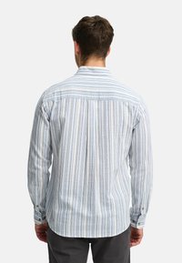 Camisa de manga larga en un patrón de rayas azul claro y blanco, con cuello y puños abotonados, y un acabado de tejido texturizado.