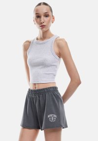 Grijze geribbelde crop top gecombineerd met losse donkergrijze shorts met een elastische tailleband en het "NEWYORK" logo in het wit.
