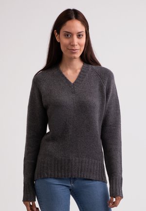 Grauer Strickpullover mit V-Ausschnitt, gerippten Bündchen und Saum. Hat eine weiche Textur und eine leicht lockere Passform, getragen über blauen Jeans.