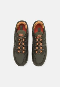 Olivno zeleni Nike Air športni copati z teksturirano zgornjimi deli, oblazinjeno pomarančno podlogo in izdelanimi vezalkami s bakrenimi poudarki.