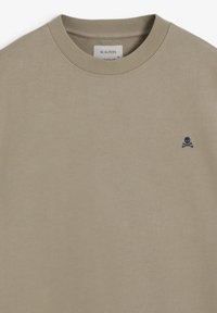 Bluza bej din bumbac cu guler rotund ribat, cu un logo mic albastru cu craniu și oase încrucișate pe pieptul stâng. Design simplu, textură moale.