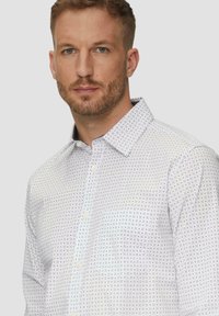 Witte button-up shirt met een klein donkerblauw ruitpatroon, met een kraag en een enkele borstzak. Katoenen stof met een gladde textuur.