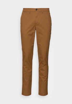 Pantalones marrones de corte entallado para hombre, con cierre de botón, trabillas para cinturón y bolsillos laterales, mostrados sobre un fondo blanco liso.