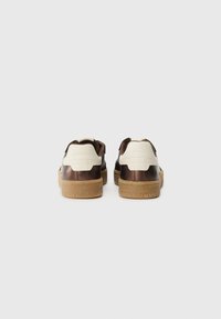 Sneakers in pelle marrone e crema con suole texturizzate, forma arrotondata e un leggero rialzo sul retro. Presentano dettagli cuciti.