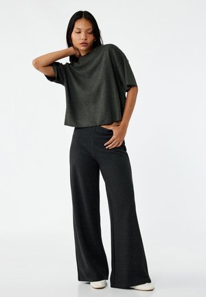 T-shirt court gris foncé avec des manches larges et courtes, assorti d'un pantalon gris foncé ample, le tout en tissu doux et texturé.