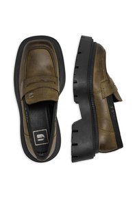 Hnedé kožené mokasíny s hrubou čiernou gumovou podrážkou, prešitie a elastické bočné panely pre jednoduché obúvanie. Minimalistický dizajn.