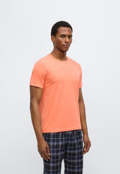 Tričko s krátkým rukávem v korálové barvě, vyrobené z měkké látky. Kulatý výstřih a úzký střih. Kombinováno s kostičkovanými pyžamovými kalhotami v modré a černé barvě.
