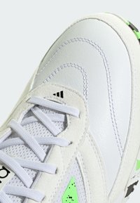 Białe sportowe buty z mieszanką gładkiej skóry i fakturowanego zamszu. Akcentowane neonowymi zielonymi detalami i białymi sznurowadłami.