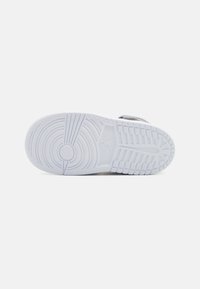 Suola di sneaker in gomma bianca con motivi circolari e lineari testurizzati, caratterizzata da un logo vicino al tallone e un design della superficie liscia.