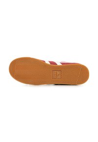 Vista inferior de una zapatilla deportiva roja con franjas blancas, suela de goma, patrón de tracción en espiga y detalles de logotipo en relieve.