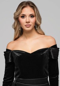 Czarna aksamitna sukienka odsłaniająca ramiona, z plisowanymi satynowymi akcentami i głębokim dekoltem w kształcie litery V, charakteryzująca się gładką fakturą i dopasowanym krojem.