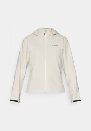 Veste imperméable beige clair avec capuche, équipée d'une fermeture éclair sur le devant, de poignets élastiques avec des accents noirs et d'un logo sur le côté supérieur gauche.