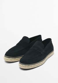 Černé semišové loafers s pletenou jute podrážkou, s prošívaným detailem na svršku a plochým designem bez šněrování nebo ozdob.