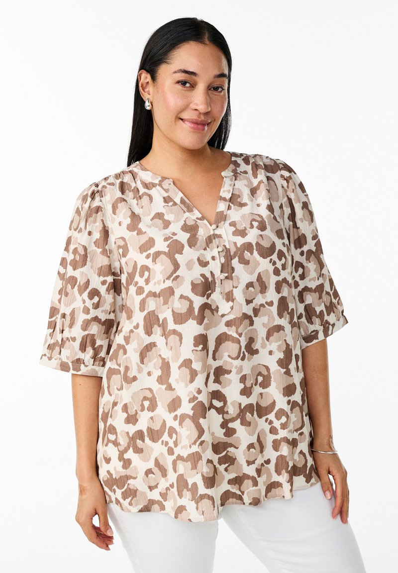 Blusa leggera di crema con stampa leopardata marrone, caratterizzata da un scollo a V e maniche corte a sbuffo. Dettaglio dei bottoni sul décolleté.
