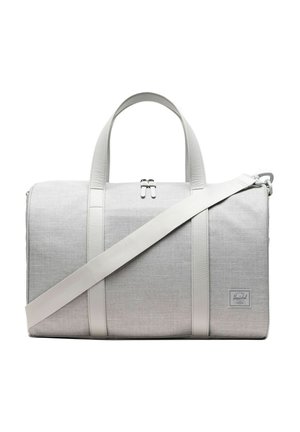 Sac de voyage en tissu gris clair avec deux poignées courtes, une longue bandoulière réglable et une fermeture éclair sur le dessus.