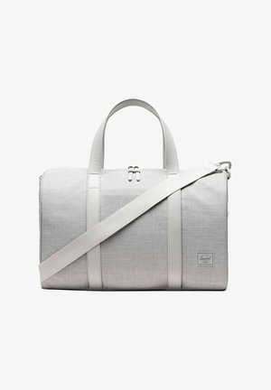 Sac de voyage en tissu gris clair avec deux poignées courtes, une longue bandoulière réglable et une fermeture éclair sur le dessus.