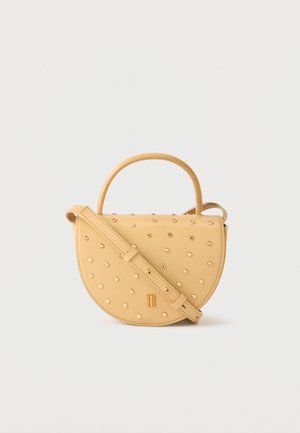 Geantă galbenă în formă de semicerc cu nituri aurii, mâner scurt și curea de umăr reglabilă pe un fundal simplu.