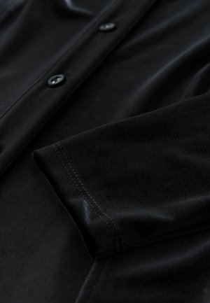 Cardigan din amestec de bumbac de culoare neagră, cu o textură netedă, având închidere cu nasture și cusături ordonate pe mansete și pe cusături.