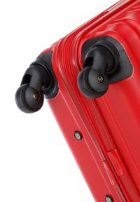 Red hard-shell suitcase with textured surface, dual black wheels, and zipper closure. Features corner protectors and smooth rolling design.