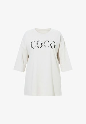 Hvid oversized t-shirt med korte ærmer med sort og brun plettet "COCO" grafisk tryk. Blødt bomuldsstof, afslappet pasform.