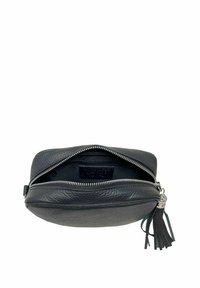 Borsa nera in pelle con superficie testurizzata, chiusura con zip e un'applicazione a frange. L'interno è foderato con un tessuto liscio.
