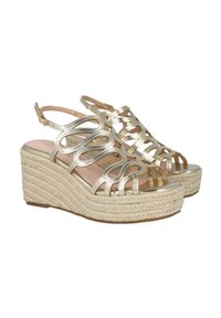 Sandalias de cuña doradas con suela de yute trenzado, múltiples correas curvas en la parte delantera y una correa para el tobillo con cierre de hebilla.